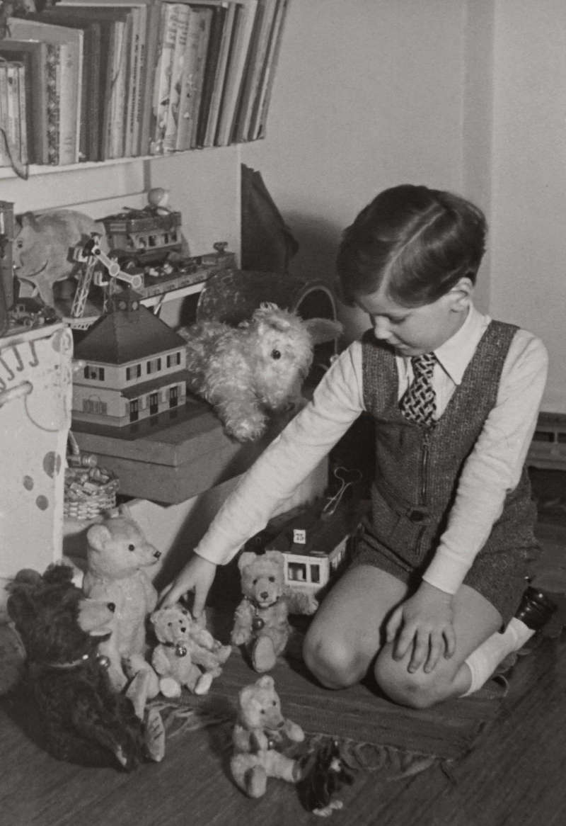 Child on the floor busy with antique teddy bears identification